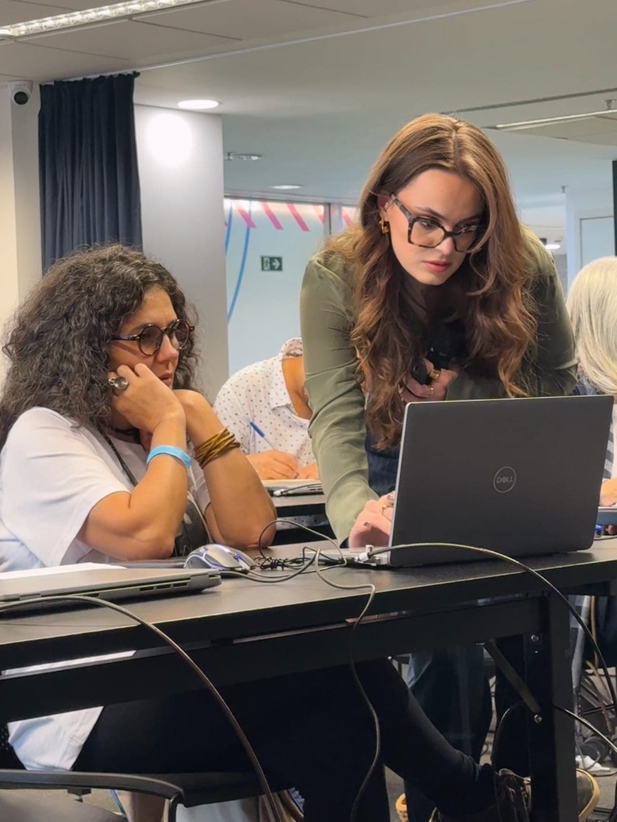 Michelle Douglas orientando uma designer no notebook durante o workshop de estamparia com IA no Senac Cápsula · ensino de moda e inteligência artificial, OUR SPACE